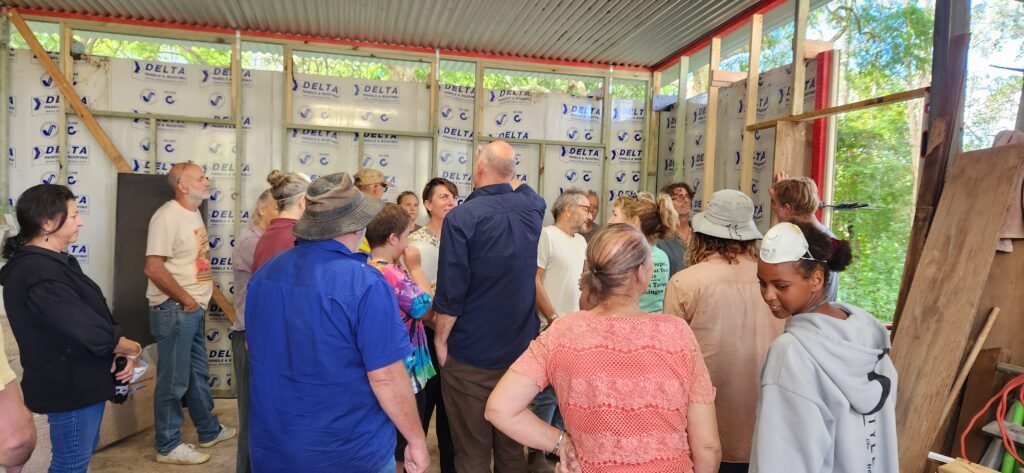 A group of people with their backs to the camera looking at a wall formed ready for building with hempcrete.