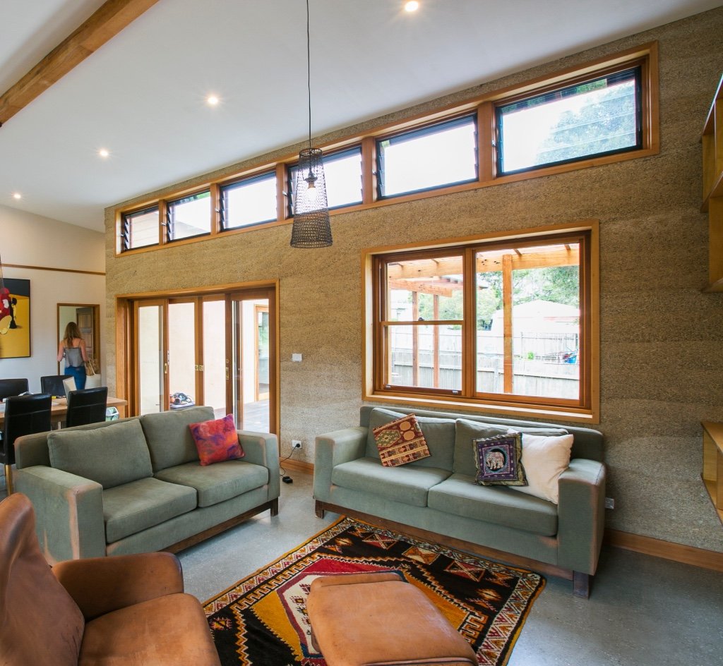 Inside of a hempcrete house showing the walls and windows from the lounge room. 